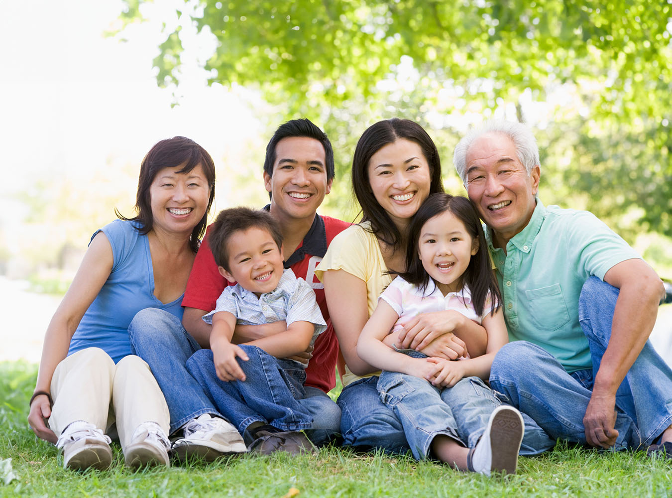 The image shows a family of five posing together outdoors, with the adults smiling at the camera and the children looking directly ahead.