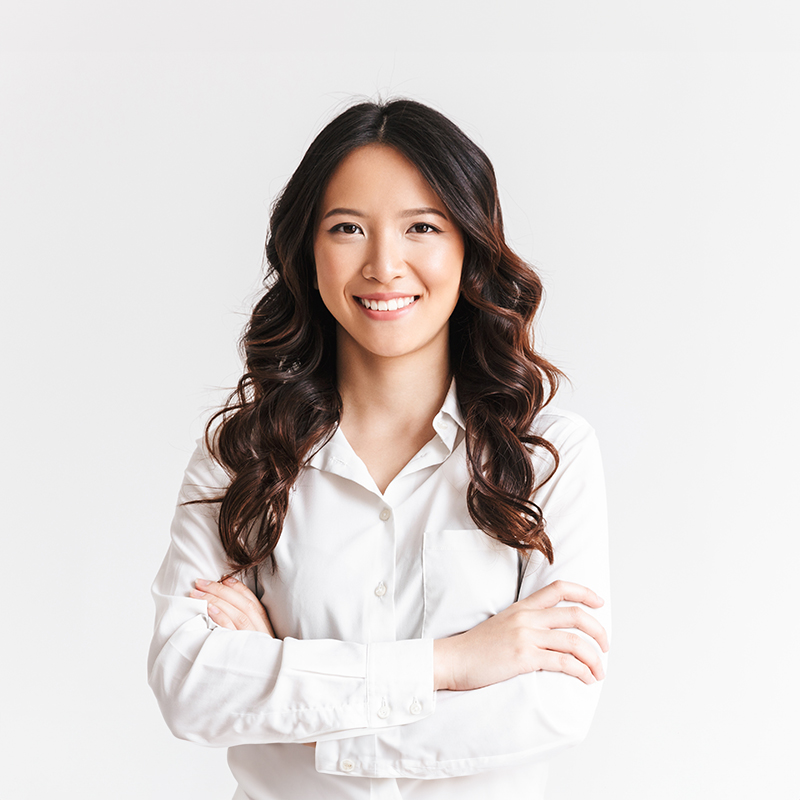 A smiling Asian woman with long hair, standing confidently with her arms crossed.