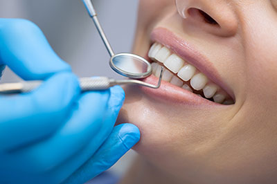 A dental professional performing oral care on a patient s teeth with a drill.
