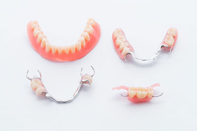 The image displays three sets of dentures with teeth in various states of wear, placed on a white background.