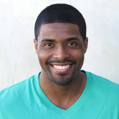 The image depicts two elderly individuals, a man and a woman, seated closely together with smiles on their faces, embracing each other against an outdoor backdrop.